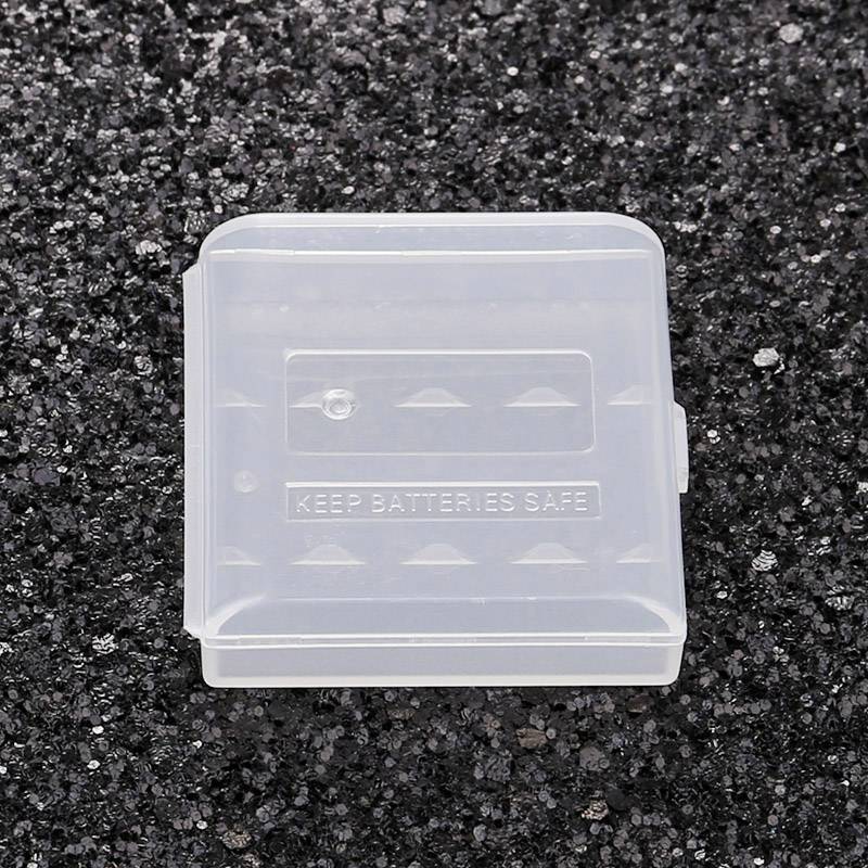 Průhledný plastový box s nápisem 'KEEP BATTERIES SAFE', ležící na tmavém povrchu, určený pro bezpečné skladování baterií.