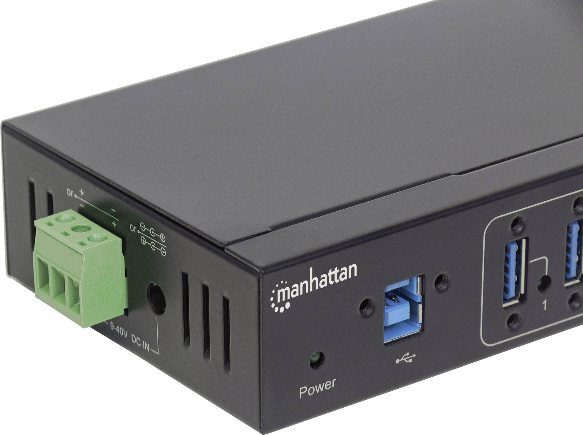Elektronické zařízení s několika USB porty a zeleným připojovacím blokem. Je viditelný název značky 'Manhattan' a síťový vypínač.