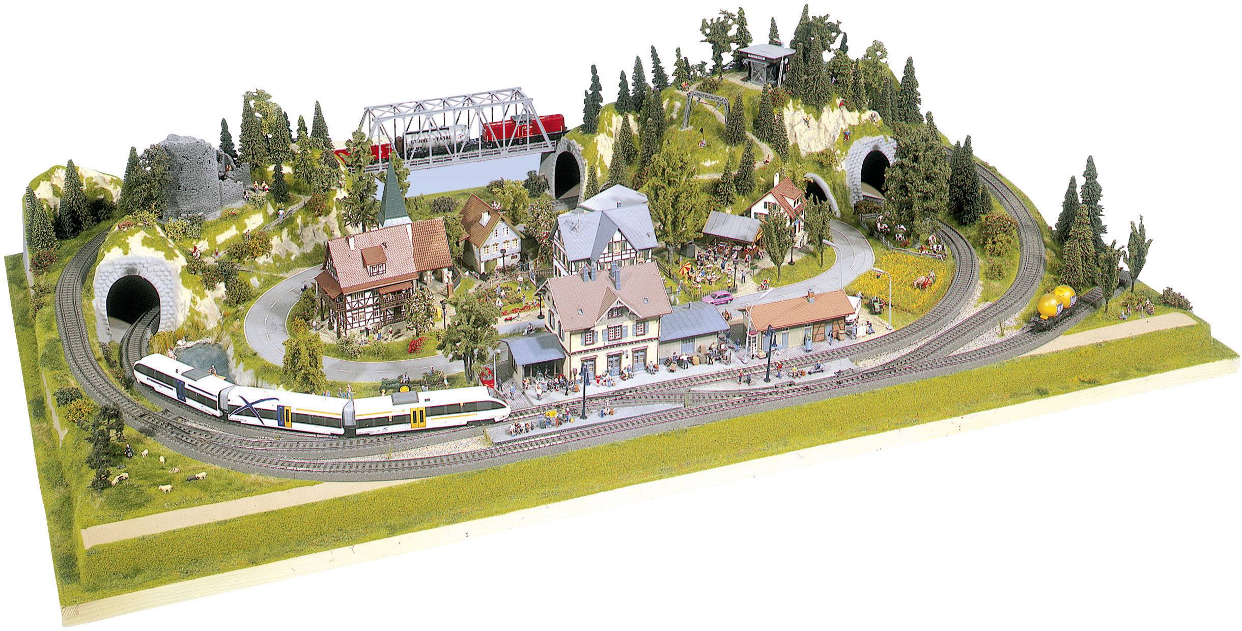 Detailní model železniční krajiny s nádražími, vlaky, mosty a krajinnými prvky jako jsou stromy a budovy.