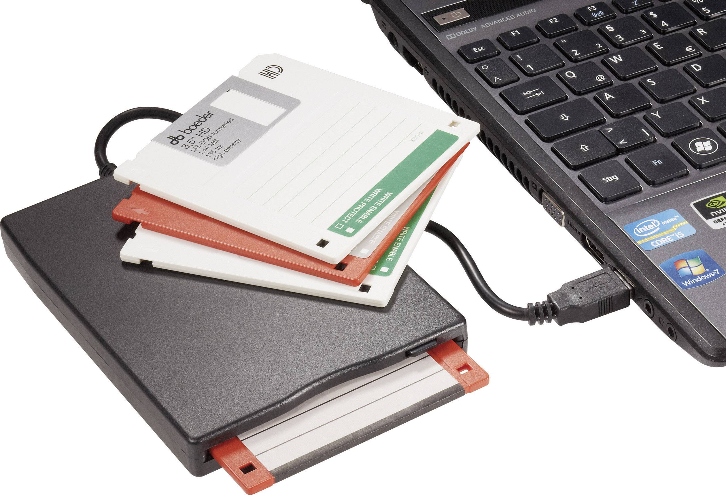 Externí disketová mechanika s několika disketami, připojená k laptopku. Firemní logo viditelné na klávesnici.