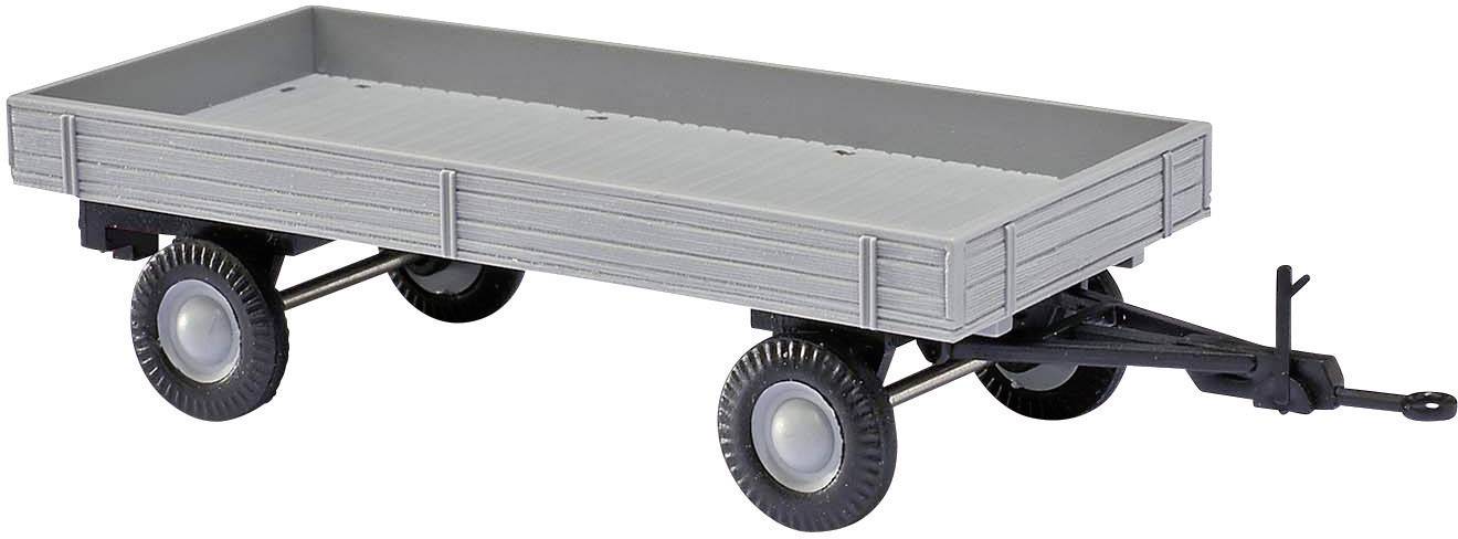 Šedý miniaturní přívěs se čtyřmi koly a plochou ložnou plochou, vhodný pro modelářství nebo hračkářské prezentace.