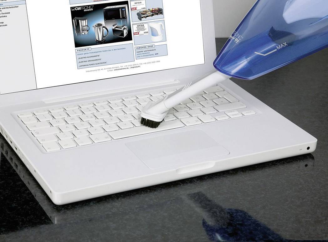 Bílý notebook je čištěn nástavcem vysavače. Na obrazovce je zobrazena webová stránka s různými domácími spotřebiči.