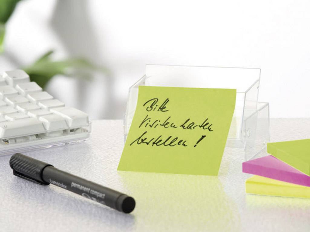 Žlutý poznámkový lístek s ručně psaným vzkazem 'Objednat vizitky!' leží vedle pera na psacím stole.