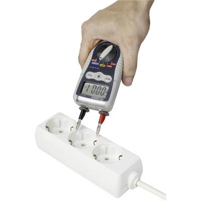 Jedna ruka drží multimetr, který měří elektrický proud v rozvodné liště. Na displeji je zobrazeno '0.000'.