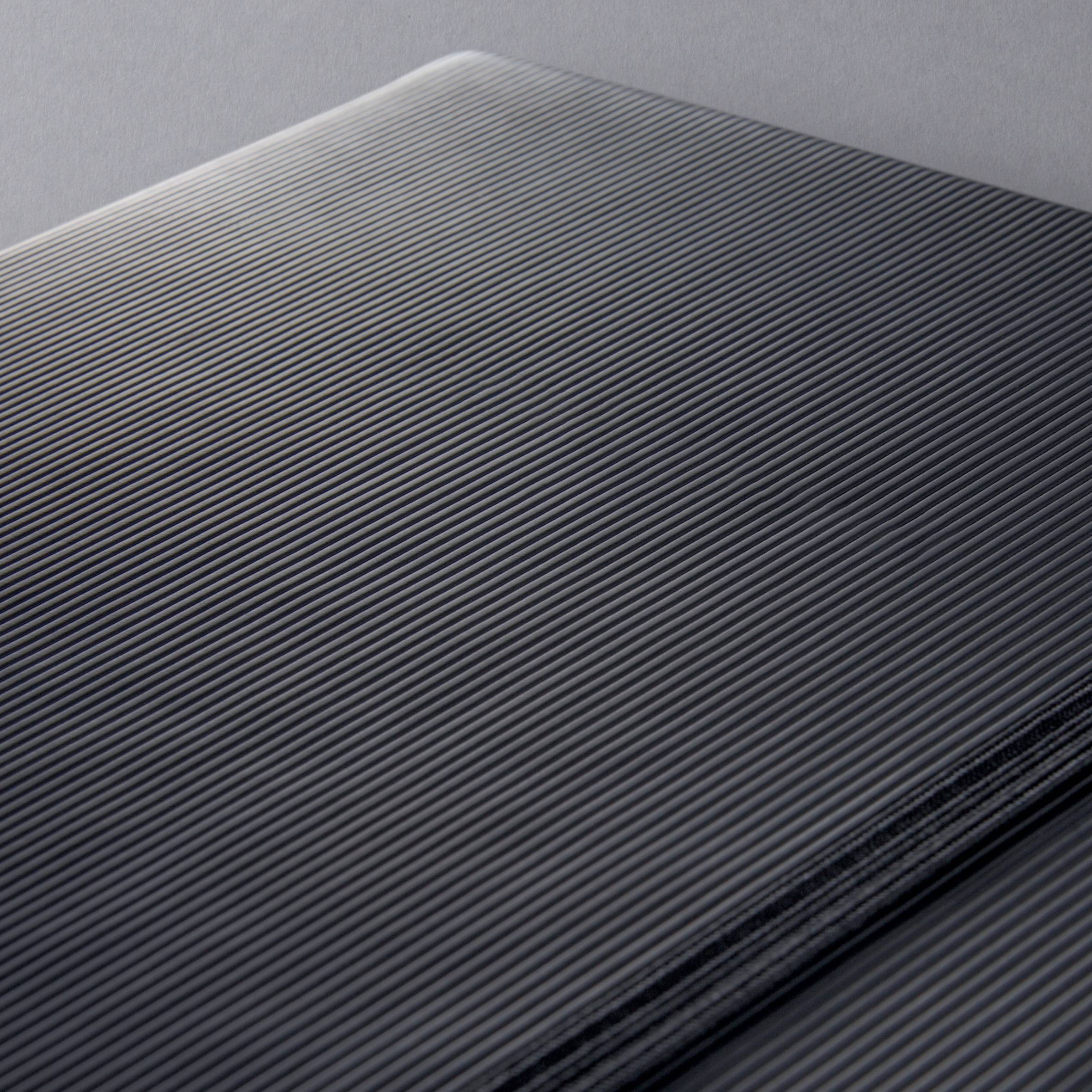Detailní záběr matně černého povrchu notebooku s jemnými linkami, který propůjčuje hladkou a elegantní texturu.