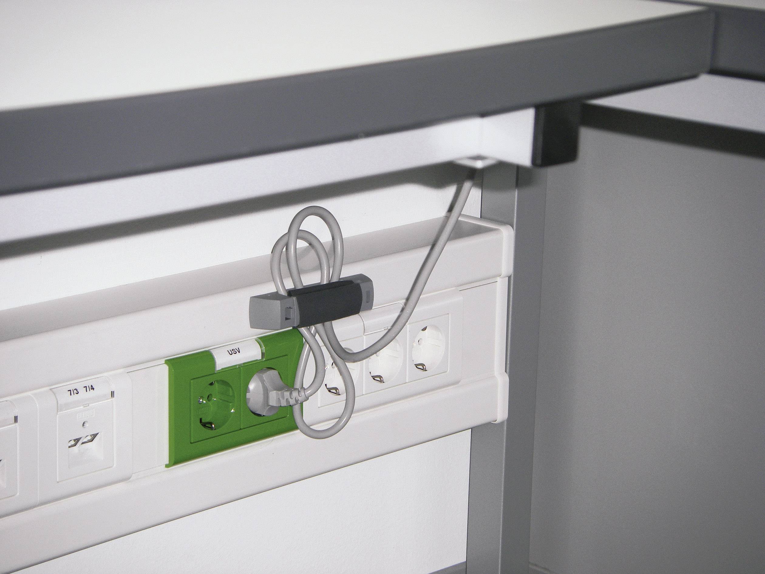 Psací stůl s rozvodnou elektrickou lištou umístěnou pod deskou. Je vidět několik elektrických zásuvek a USB portů. Jeden kabel je zapojen.