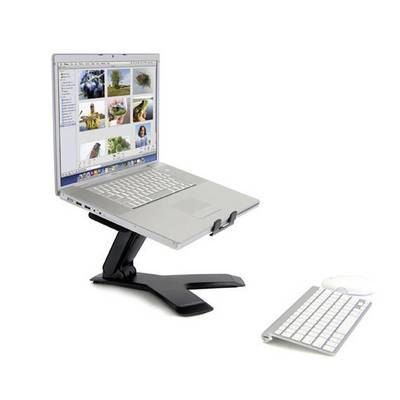 Laptop stojí na černém stojanu, jehož obrazovka zobrazuje obrázky. Před ním leží externí klávesnice a myš.