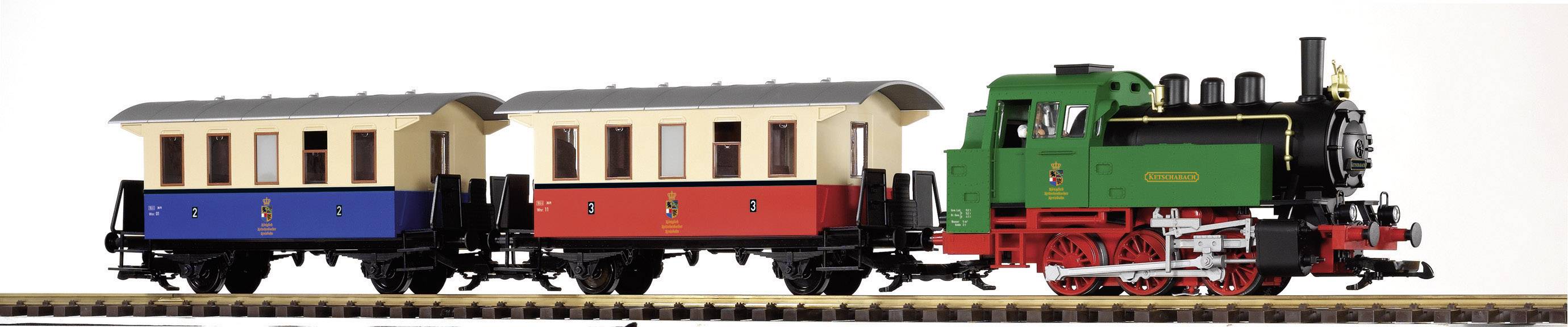 Zelený hračkový vlak se dvěma vagóny, jeden modrý a jeden červený, stojí na kolejích. Vlak má lokomotivu s komínem.