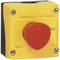 Žlutý nouzový vypínač s červeným tlačítkem. Vypínač je zabudován v obdélníkovém krytu a upevněn čtyřmi šrouby.