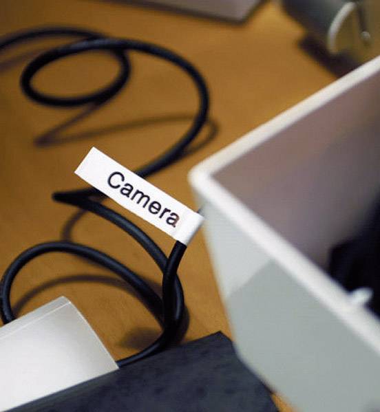 Kabel s nálepkou s nápisem 'Camera' leží na stole vedle otevřené bílé krabice.