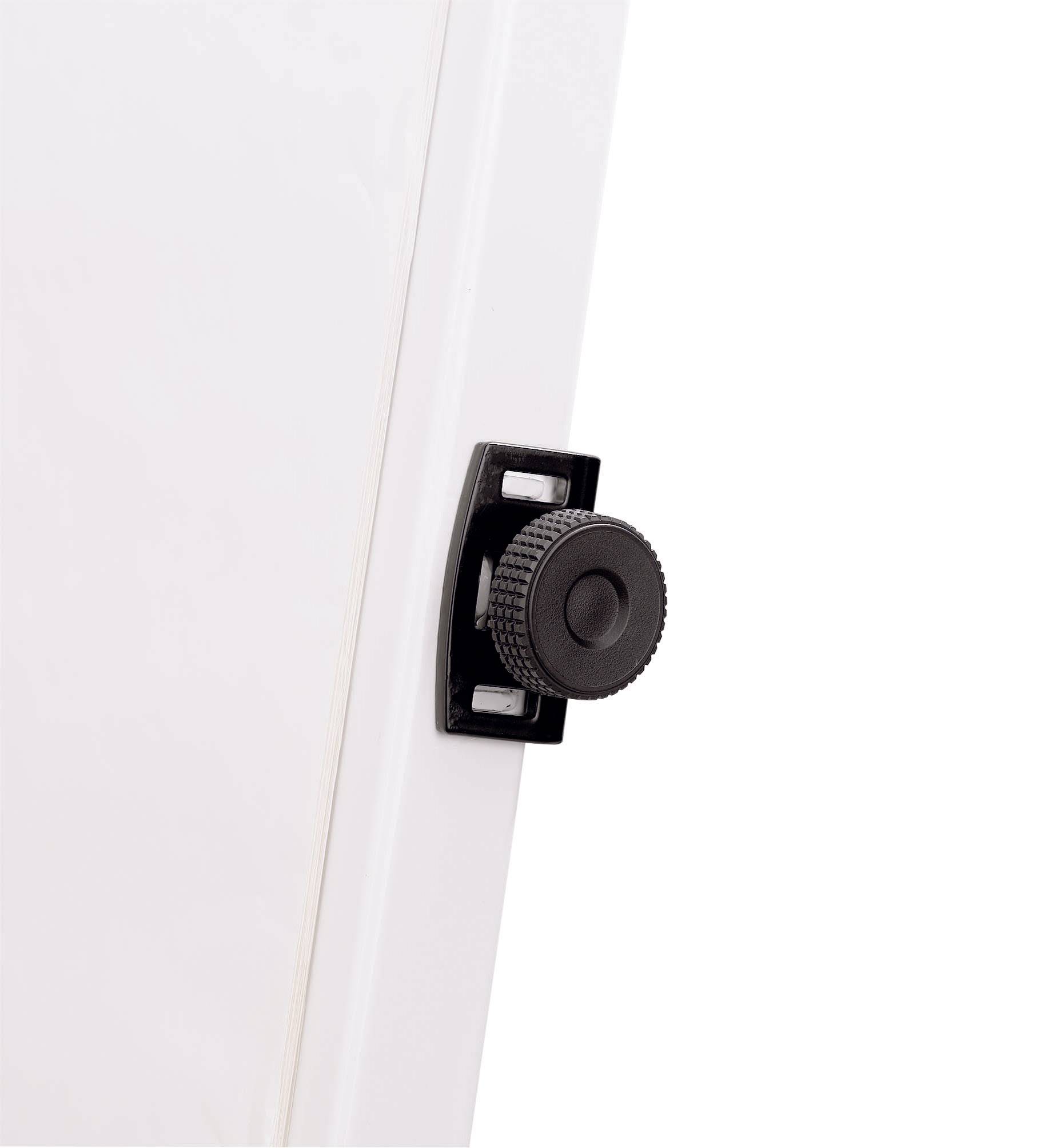 Černý otočný knoflík na straně bílého zařízení. Knoflík slouží k nastavení nebo aretaci.