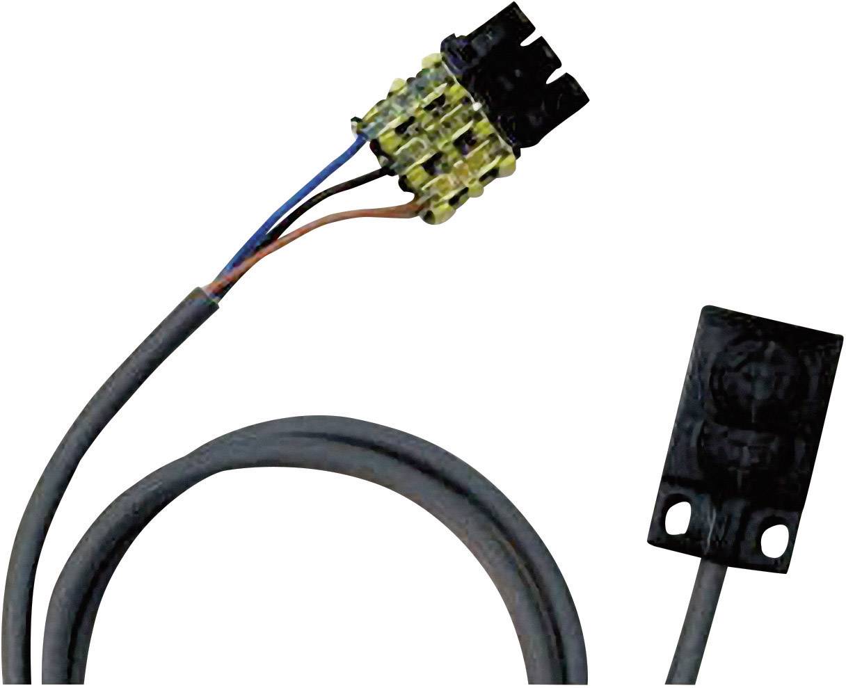 Elektrický kabel s černou zástrčkou je připojen ke konektoru. Vedle něj vpravo je vidět další černá zástrčka.