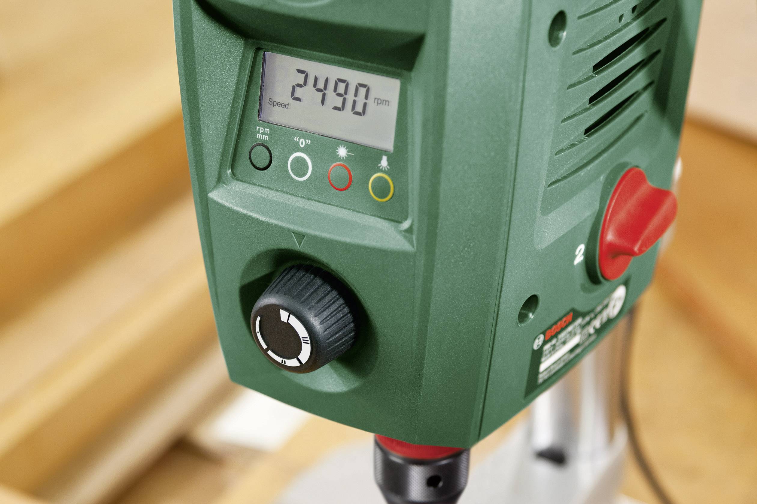 Zelená stolní vrtačka v detailním záběru. Digitální displej ukazuje otáčky '2490 ot/min'. Vlevo ovládací otočný knoflík a stavové indikátory.