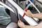 Osoba odstraňuje plastový červený nástroj z obložení dveří stříbrného automobilu.