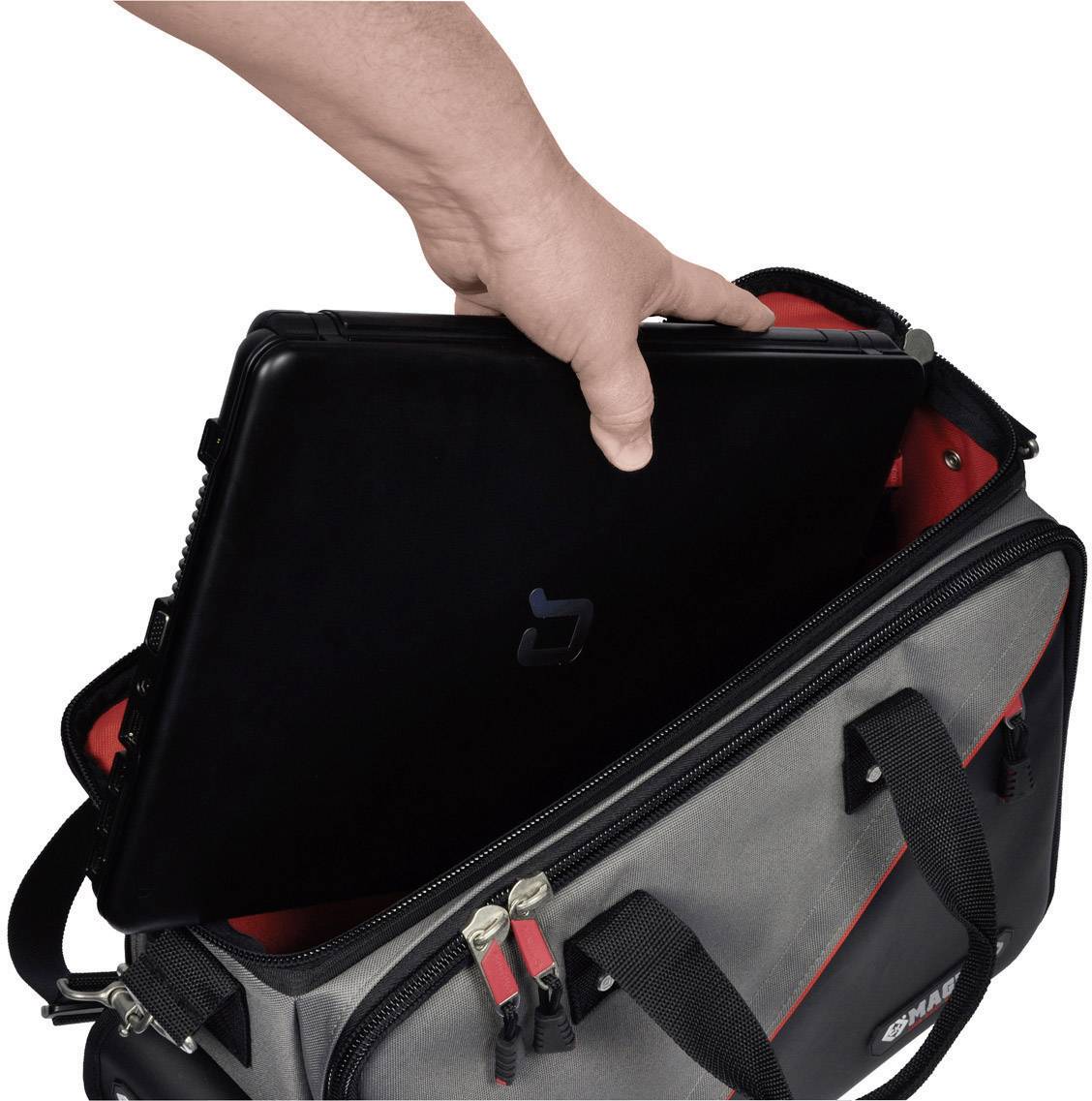 Ruka vytahuje černý notebook z šedé tašky se zipem a držadly.