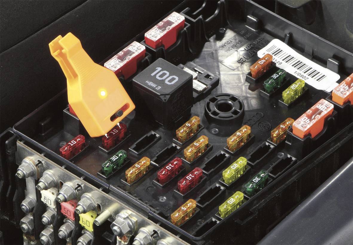Elektrické pojistky a relé v automobilovém pojistkové skříni; různé barvy a hodnoty, centrální organizace.