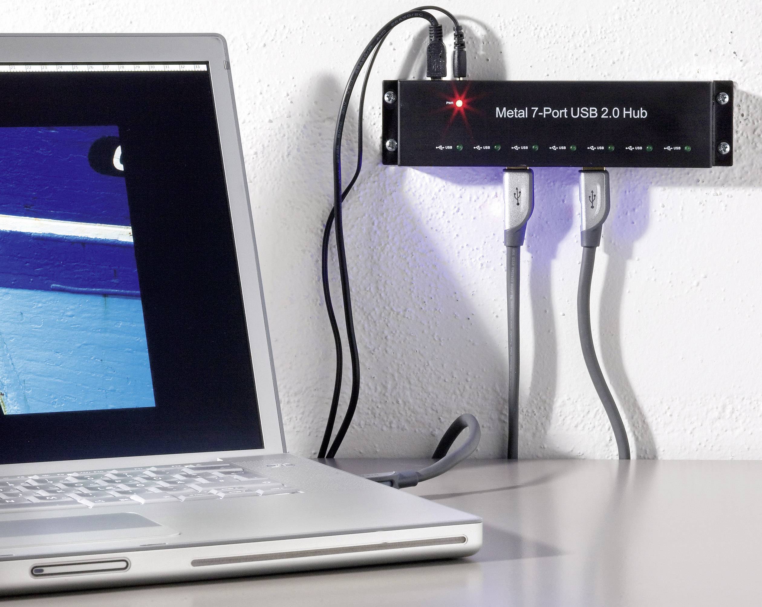 Notebook s otevřeným displejem, připojený k 7portovému USB 2.0 rozbočovači na stěně, do kterého jsou zapojeny dva kabely.
