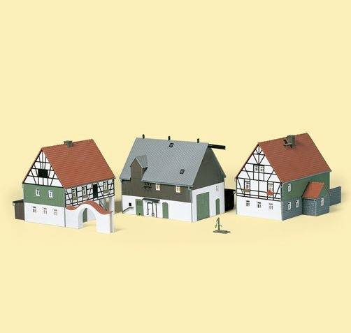 Model af tre traditionelle tysk-stilede huse med røde tage og træfagværk, sat op mod en ensfarvet baggrund.