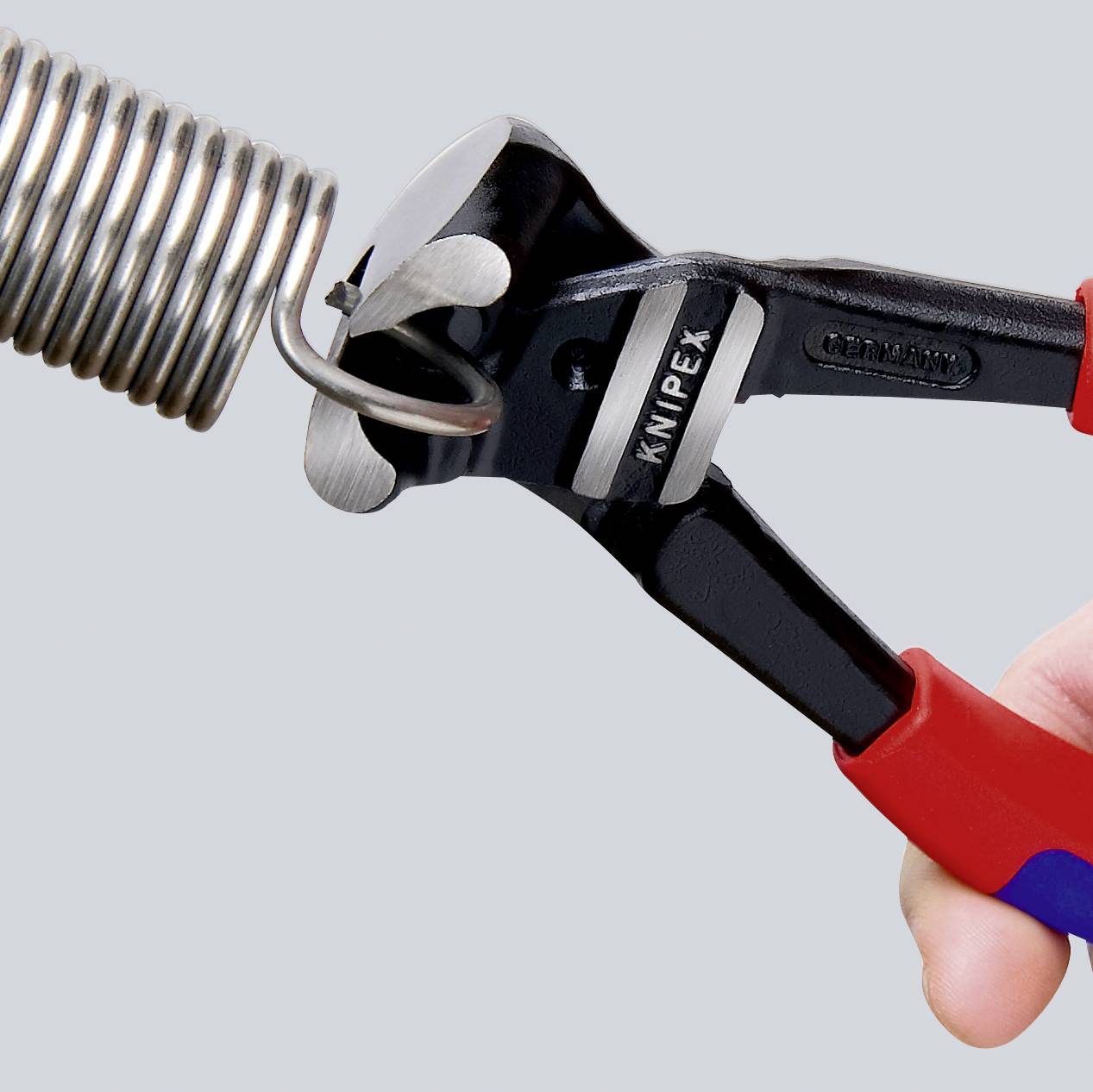 En hånd holder en Knipex-tang, der klipper en metalfjederledning.