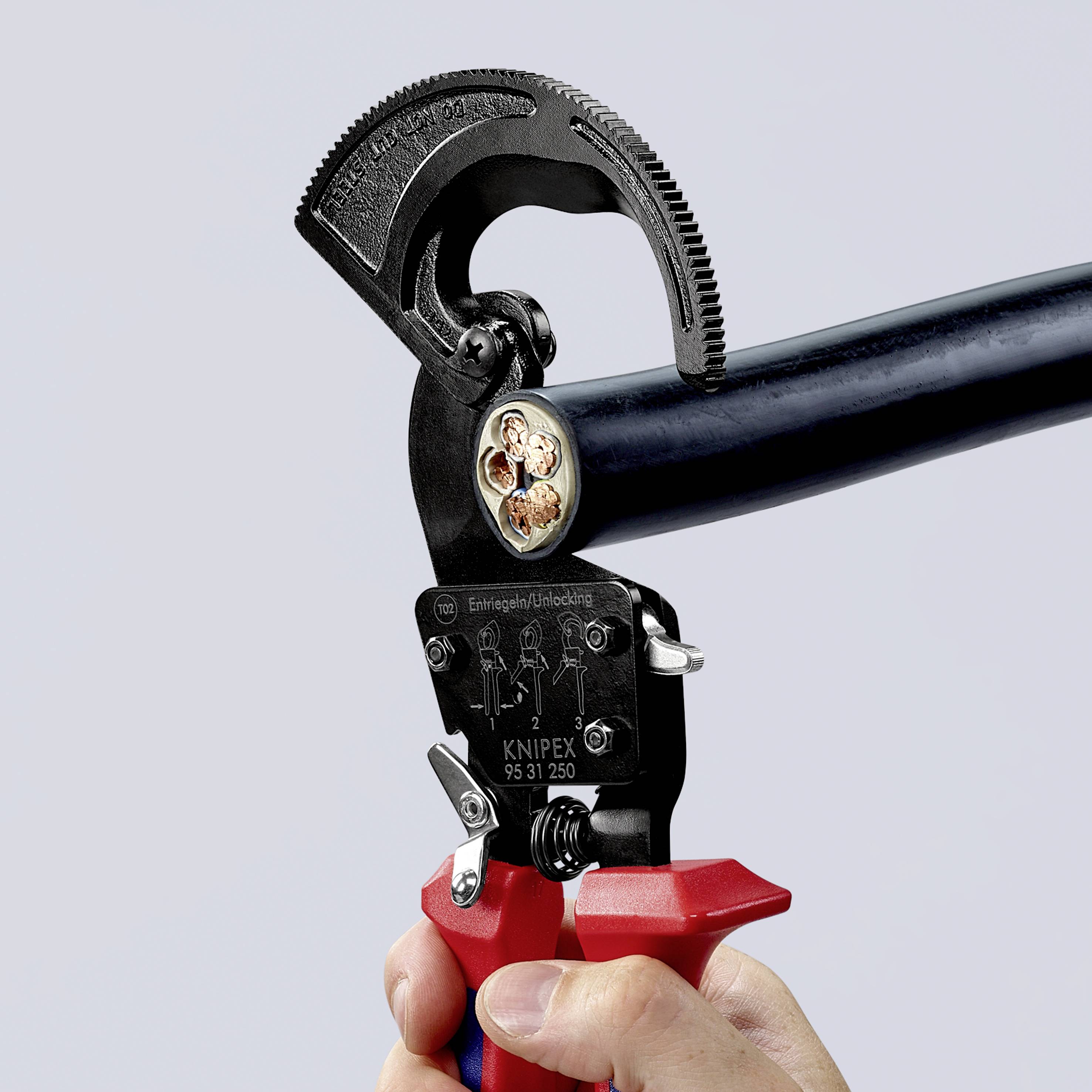 En hånd holder en KNIPEX-kabelklipper, der klipper et tykt sort kabel. Kablet viser indvendig leder og afskærmning.