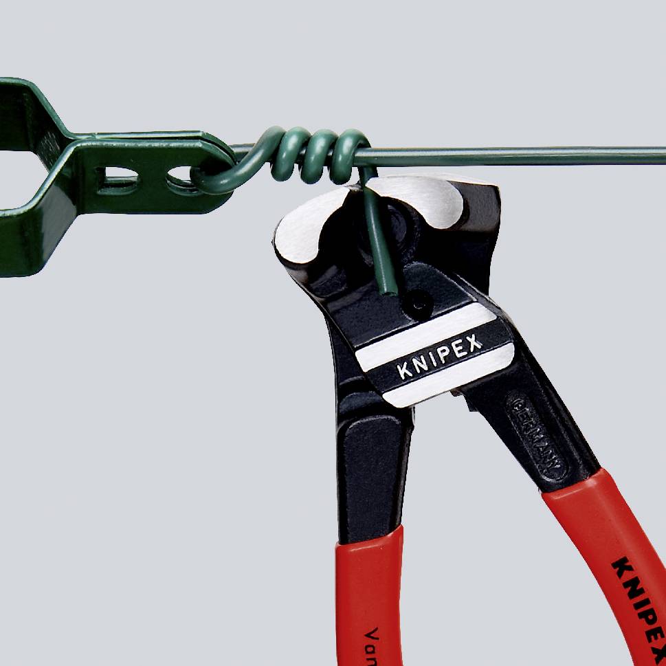 En KNIPEX-tang klipper en grøn ledning, som er fastgjort med en grøn klemme. Tangen har røde greb.