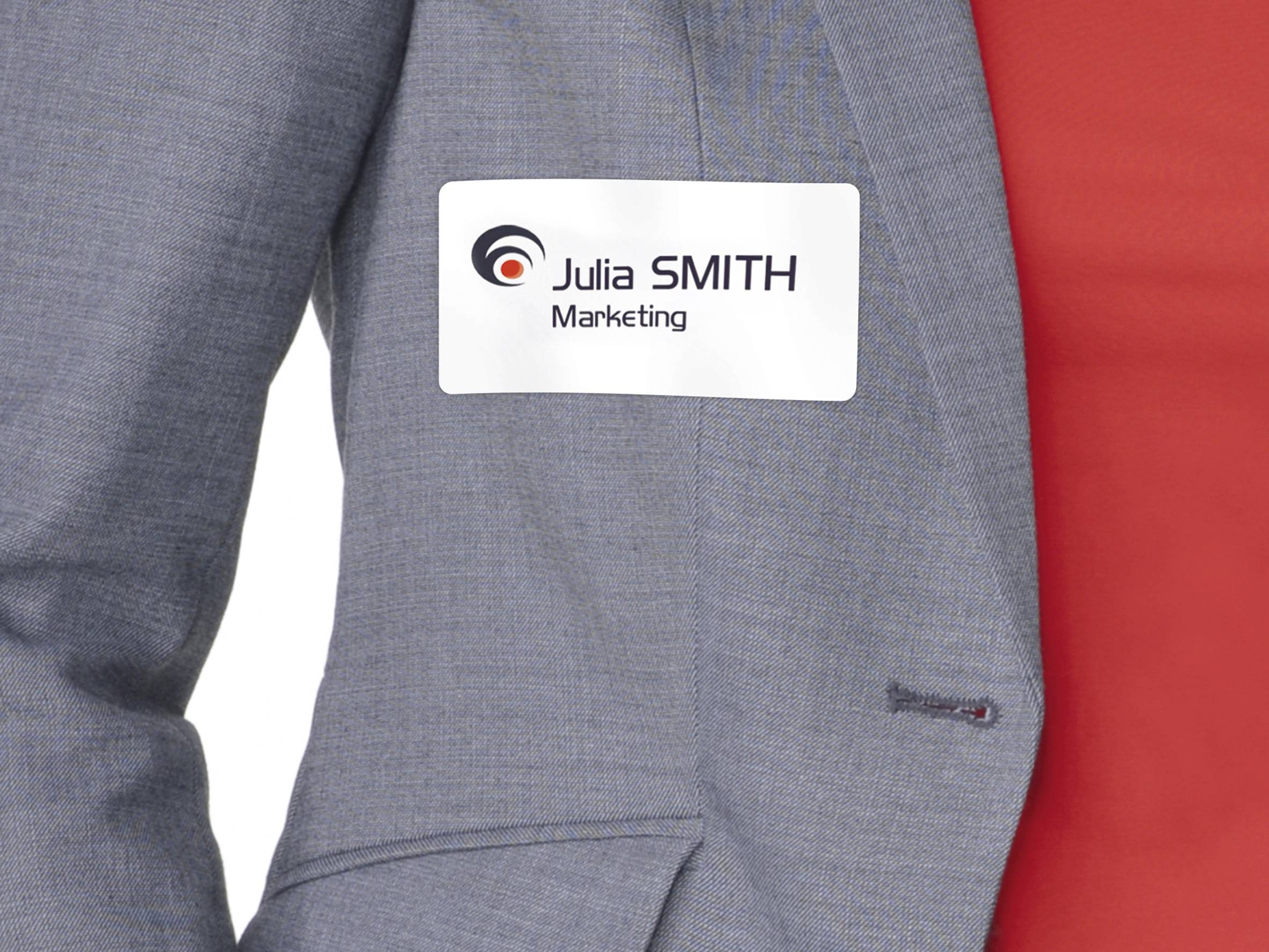 Person i grå blazer bærer navneskilt med logo og påskriften 'Julia SMITH Marketing'.