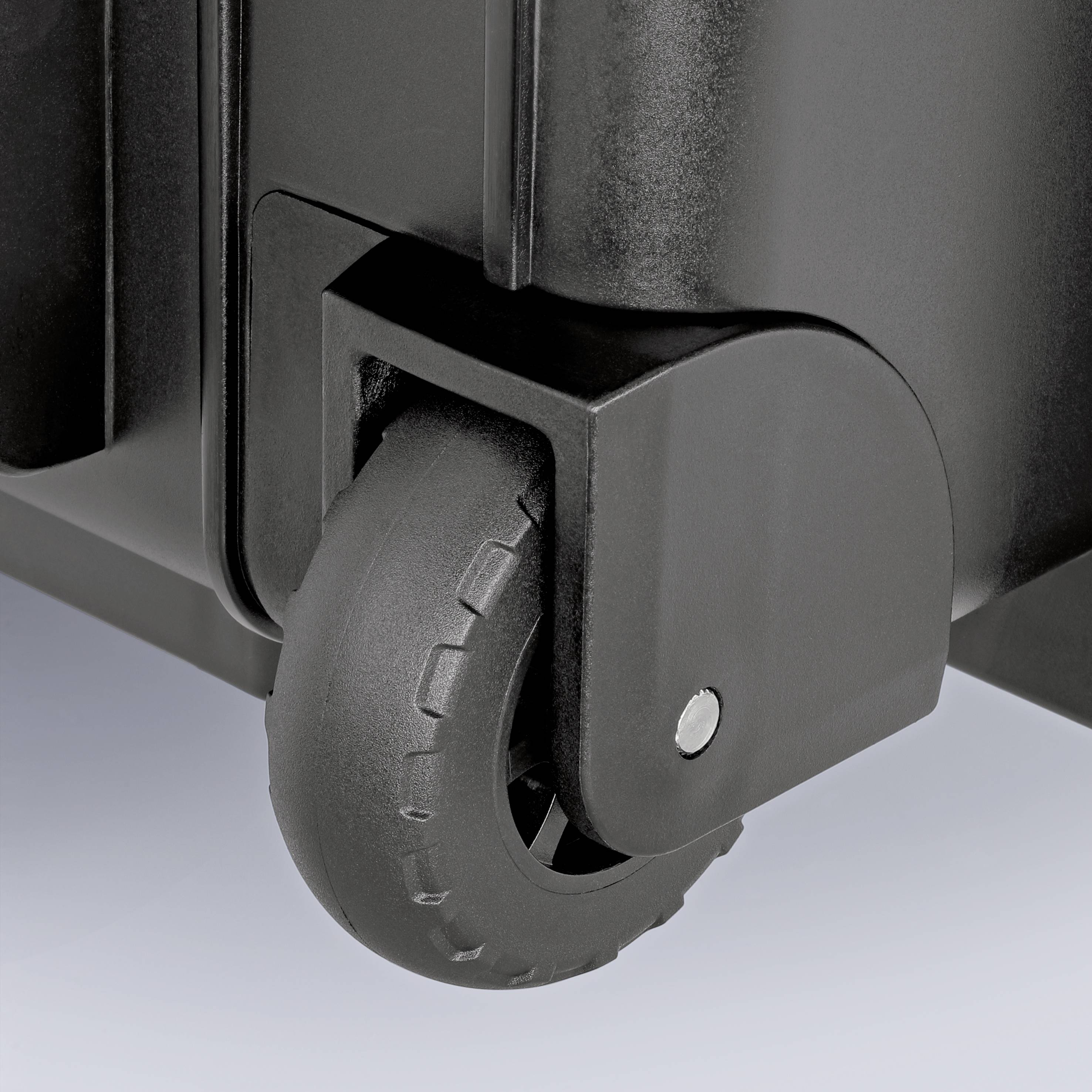 Nærbillede af en sort kuffert med et drejbart plasthjul i hjørnet, som giver stabilitet og mobilitet.