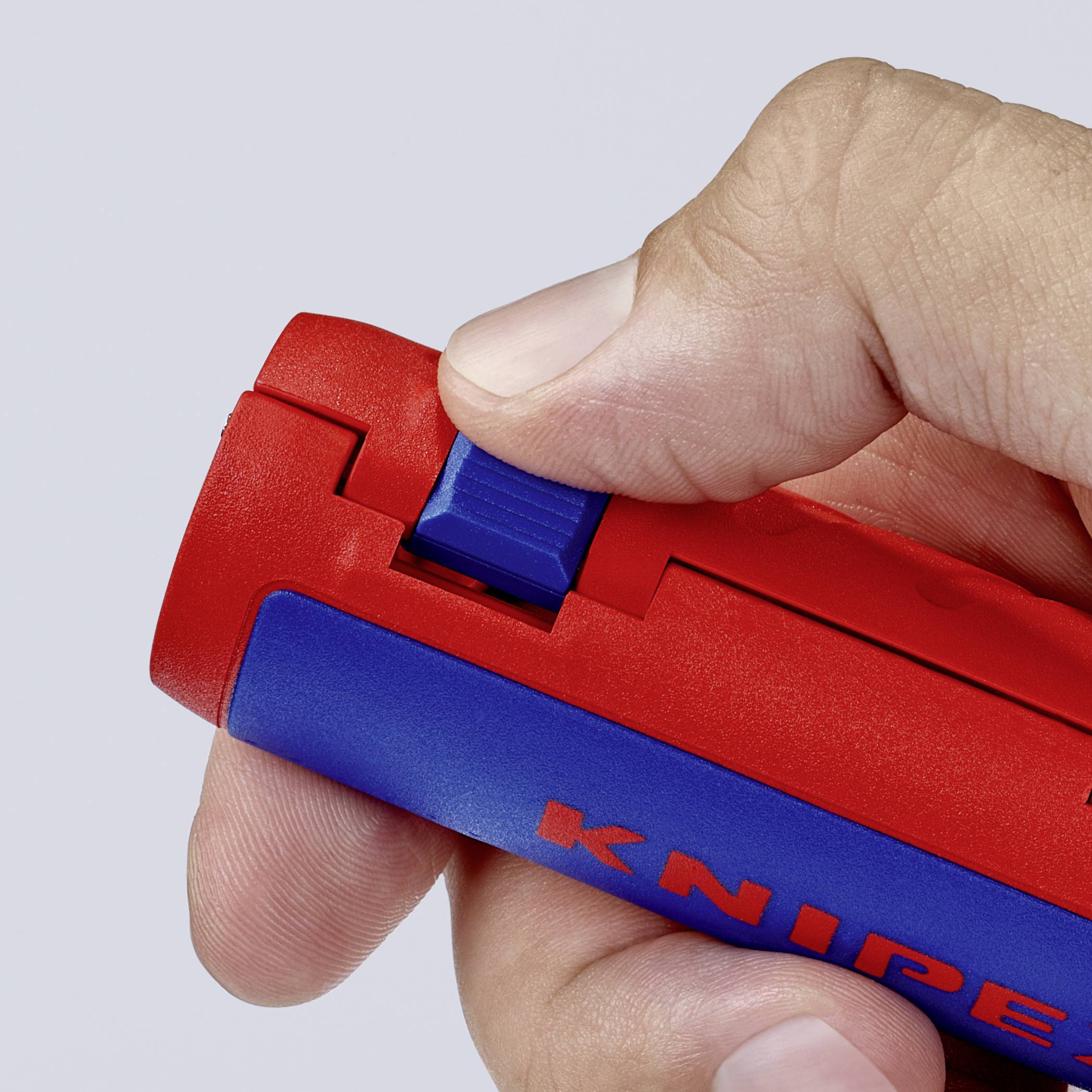 En hånd holder en rød og blå afisoleringstang fra Knipex. Tommelfingeren trykker på den blå skydemekanisme.
