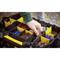 En hånd griber ind i en åben værktøjskasse, der viser forskellige typer skruer, rawlplugs og befæstelsesmaterialer.