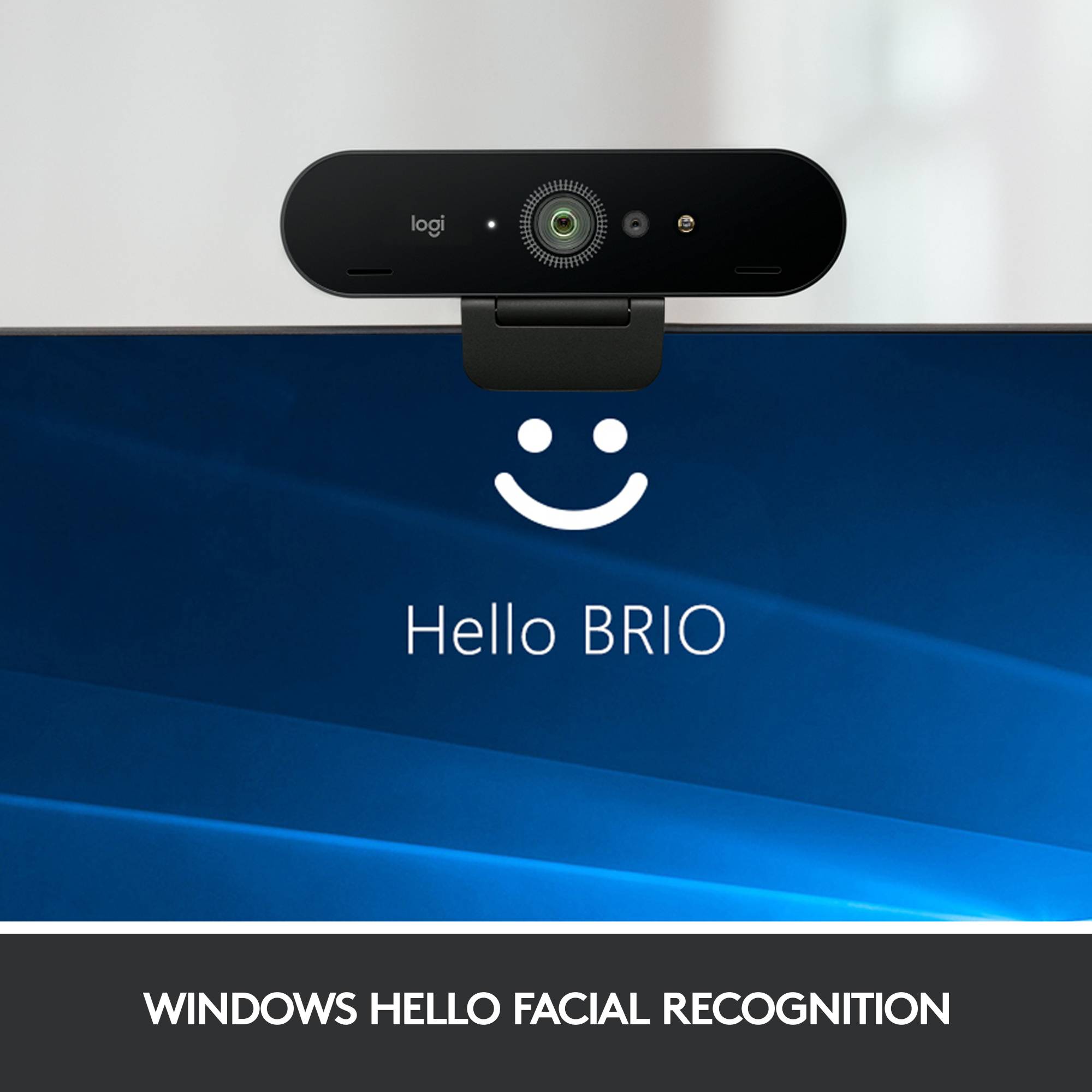 Et Logitech BRIO-webcam placeret over en skærm med et smilende ansigtssymbol og teksten 'Hej BRIO', nedenunder står der 'Windows Hello Ansigtsgenkendelse'.