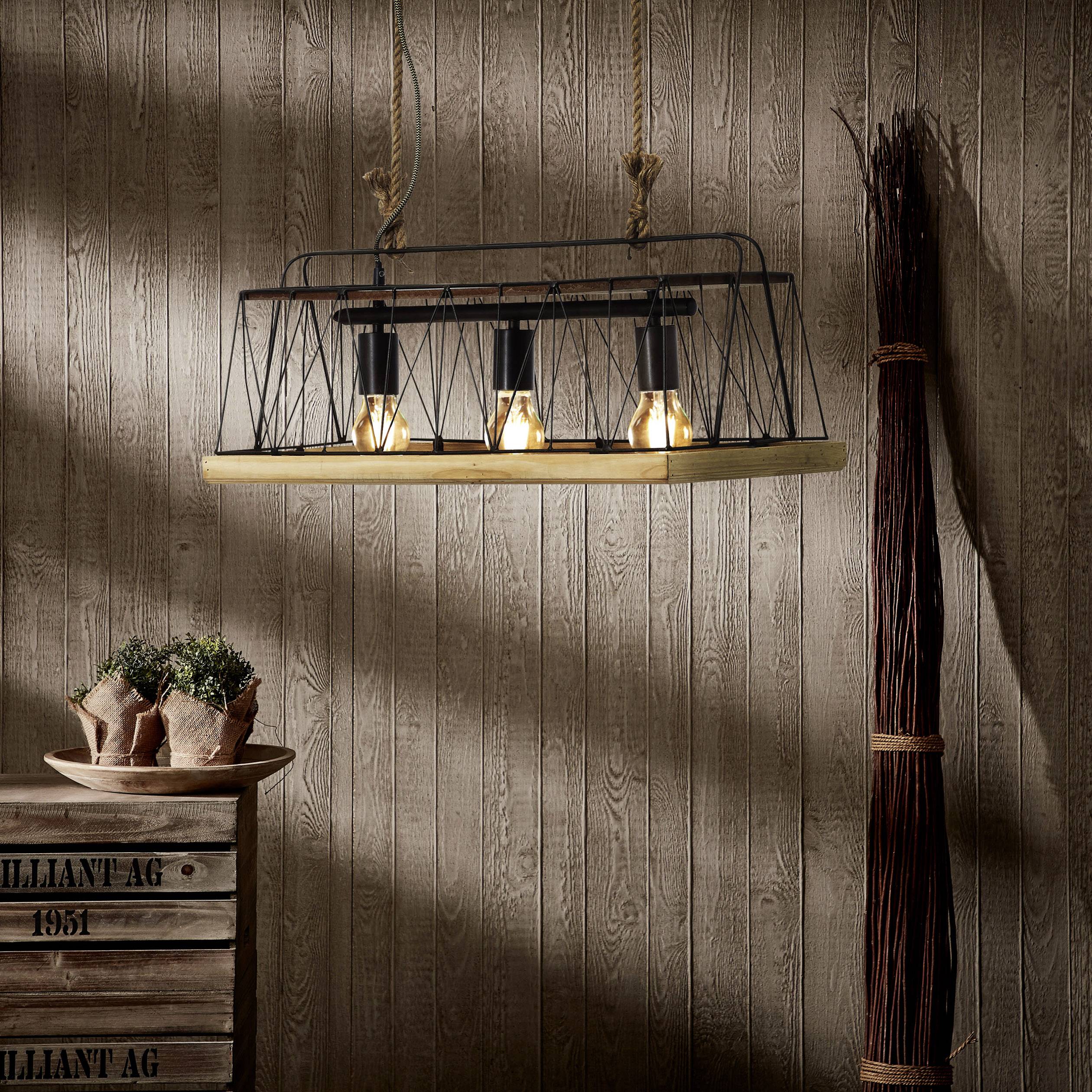 En bur-loftslampe med tre pærer hænger foran en træmur. Ved siden af står en dekorativ gren og en træboks.