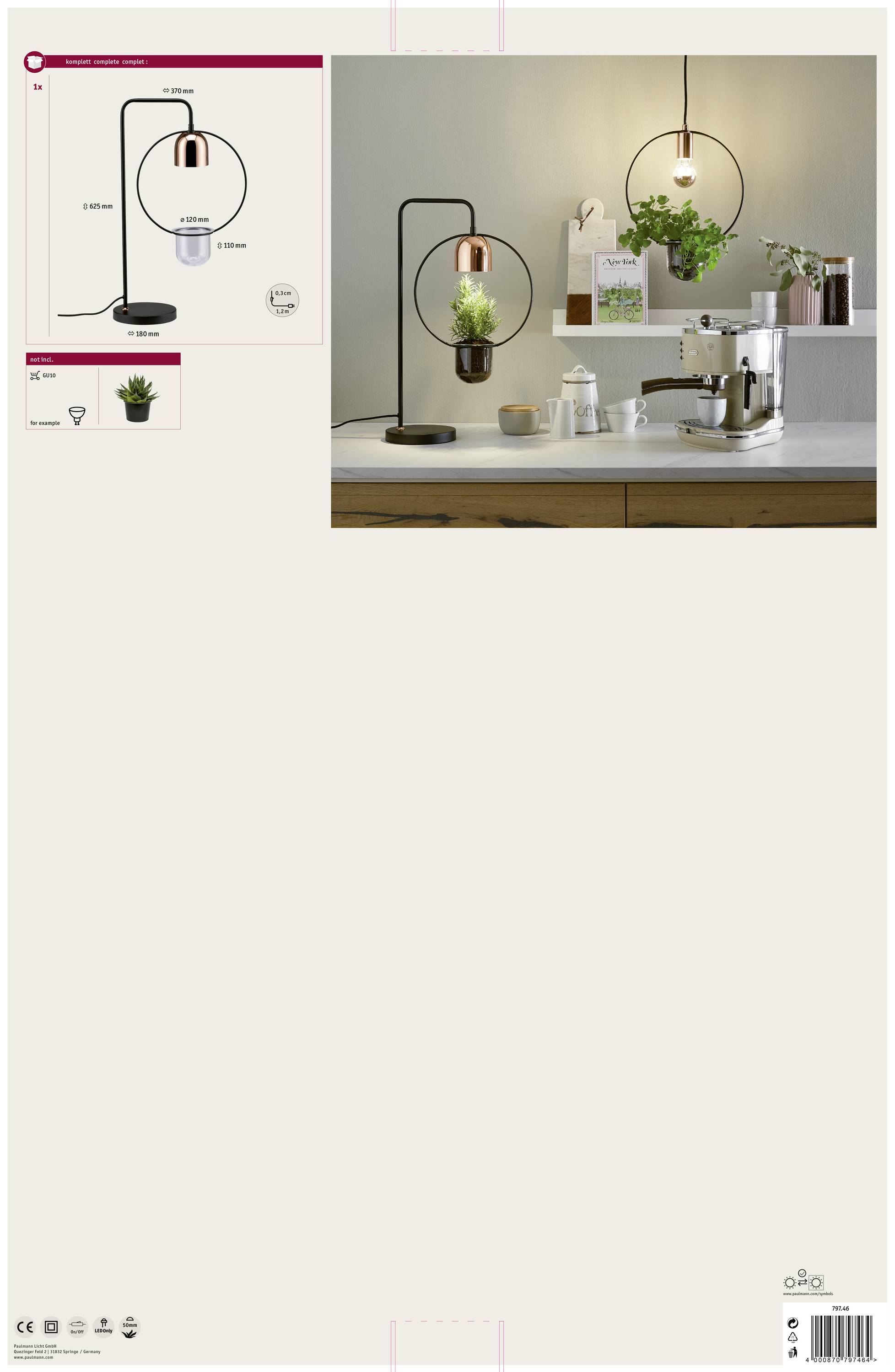 Bordlampe i moderne design med plantekrukke, der oplyser et hvidt køkken. Hænger over et bord med kaffemaskine og grønne planter.