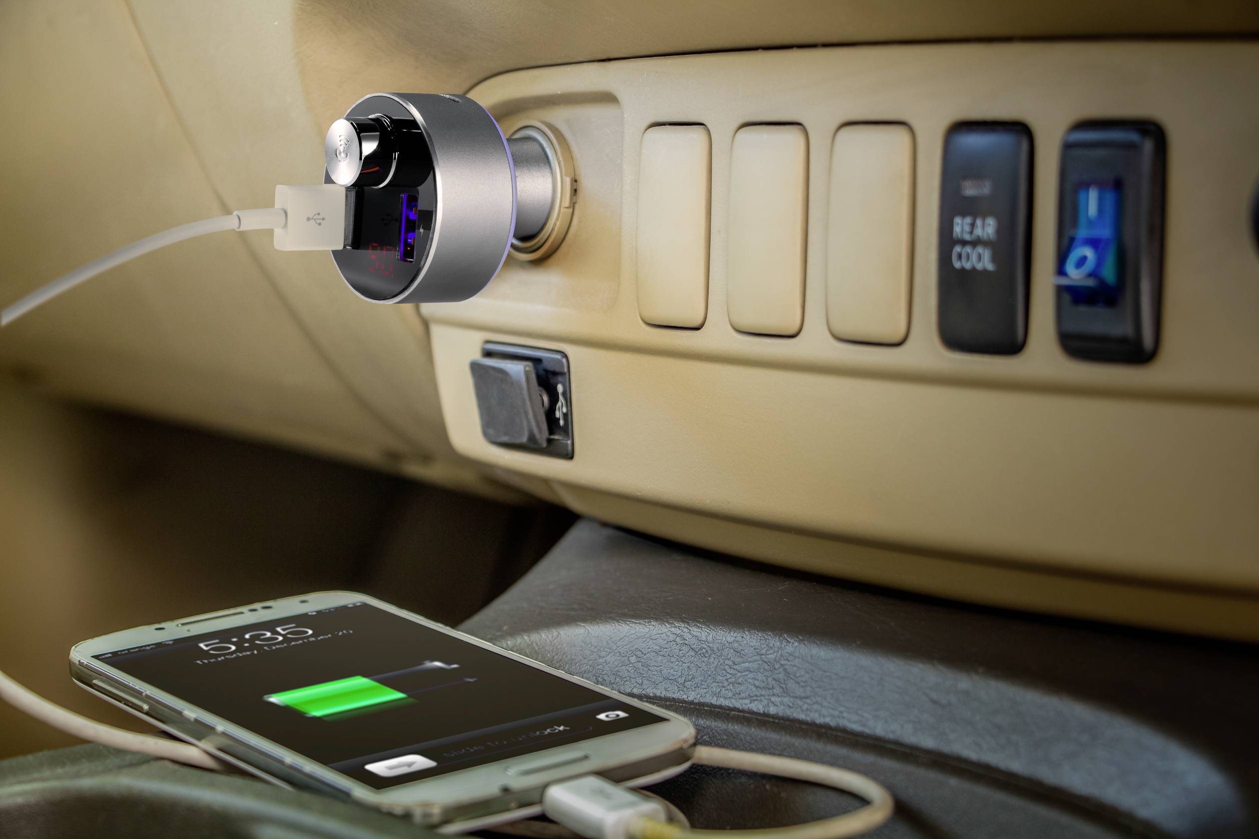 En smartphone oplades i bilen ved hjælp af et USB-kabel, som er tilsluttet en oplader i cigarettænderens stikplads.