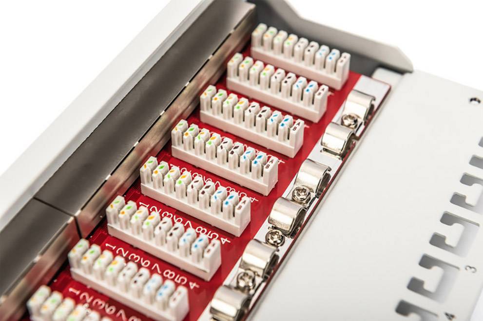 Nærbillede af et patchpanel med flere farvede Ethernet-kabelforbindelser. Enheden er designet til netværkskabler.