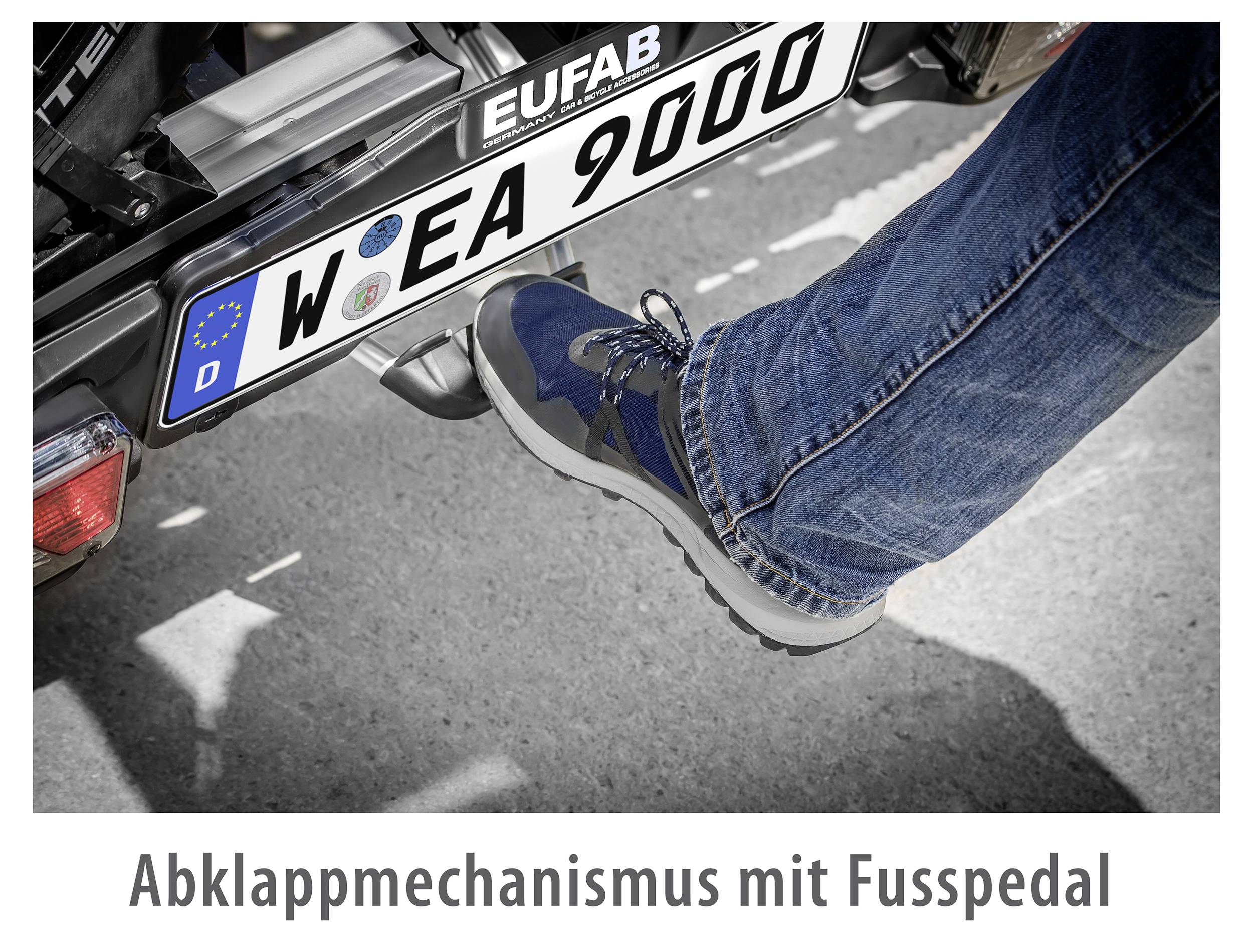 En person træder på fodpedalen på en cykelholder for at aktivere dens foldemekanisme.