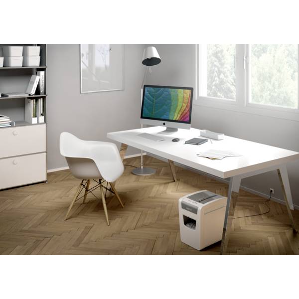 Et moderne kontor med et skrivebord, hvorpå der er en computer med en farverig skærm, en lampe, bøger og en stol.