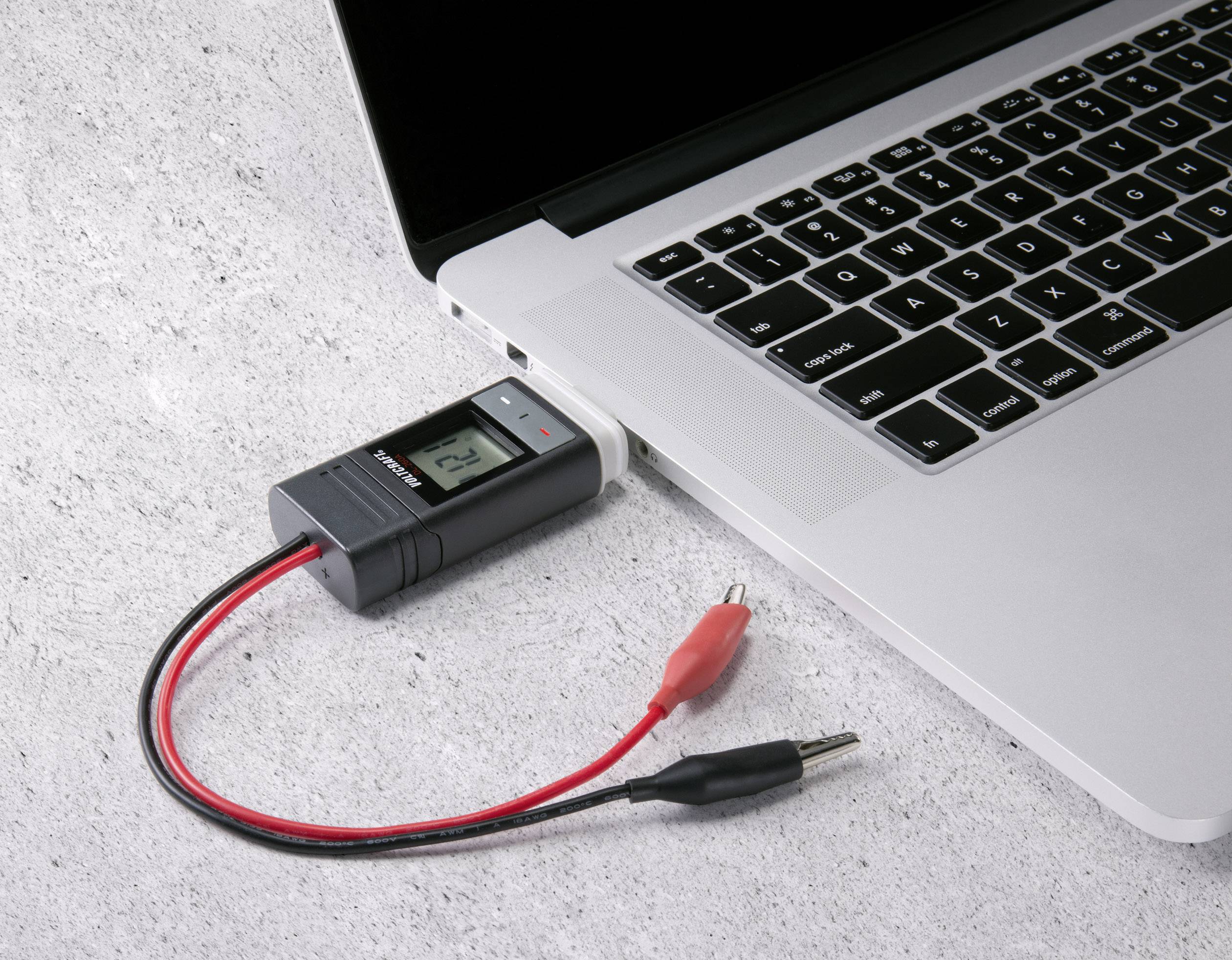 En bærbar computer med et multimeter tilsluttet via USB. Multimeteret viser en værdi på 2,4.