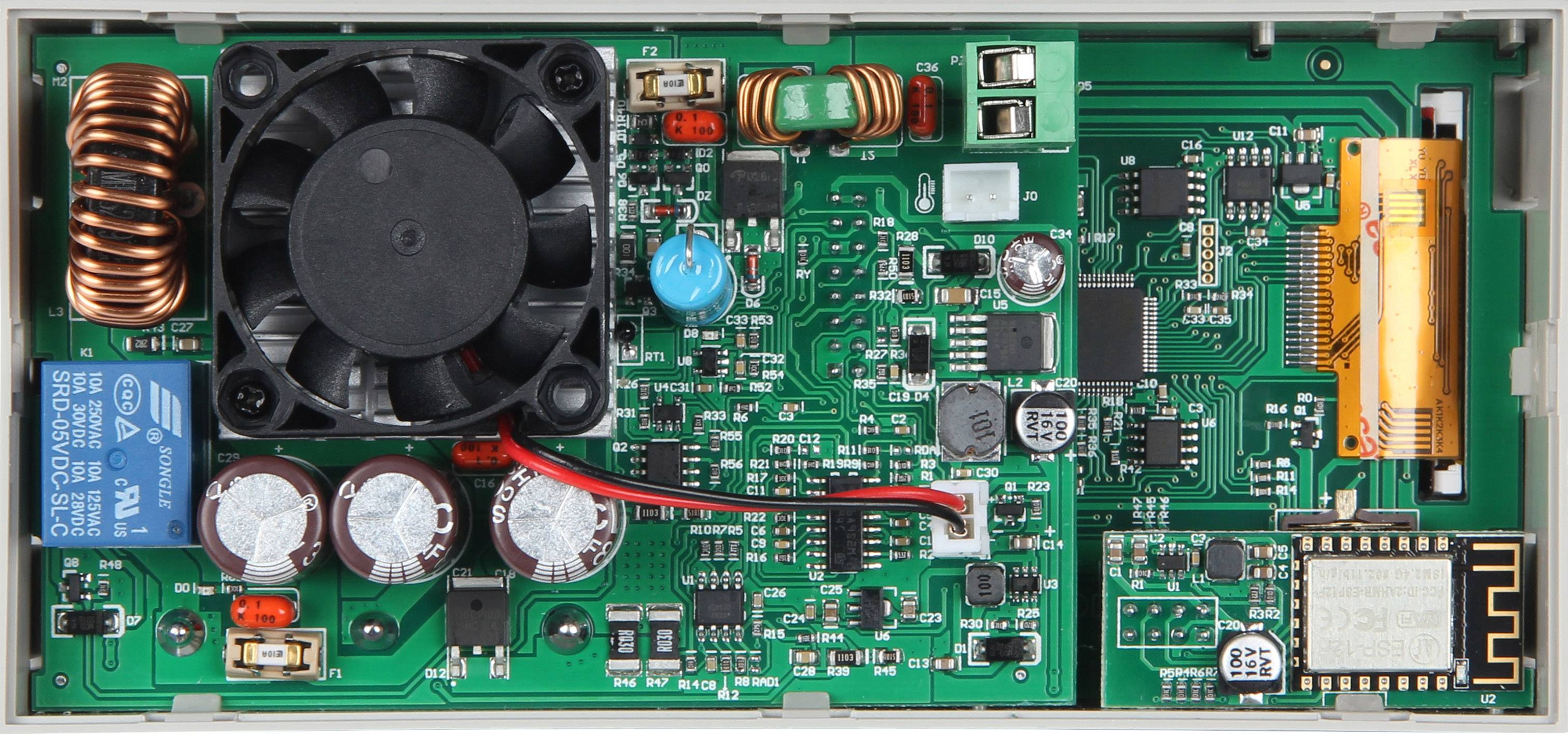 Nærbillede af et elektronisk kredsløbskort med ventilator, spoler og forskellige elektriske komponenter, monteret i et kabinet.