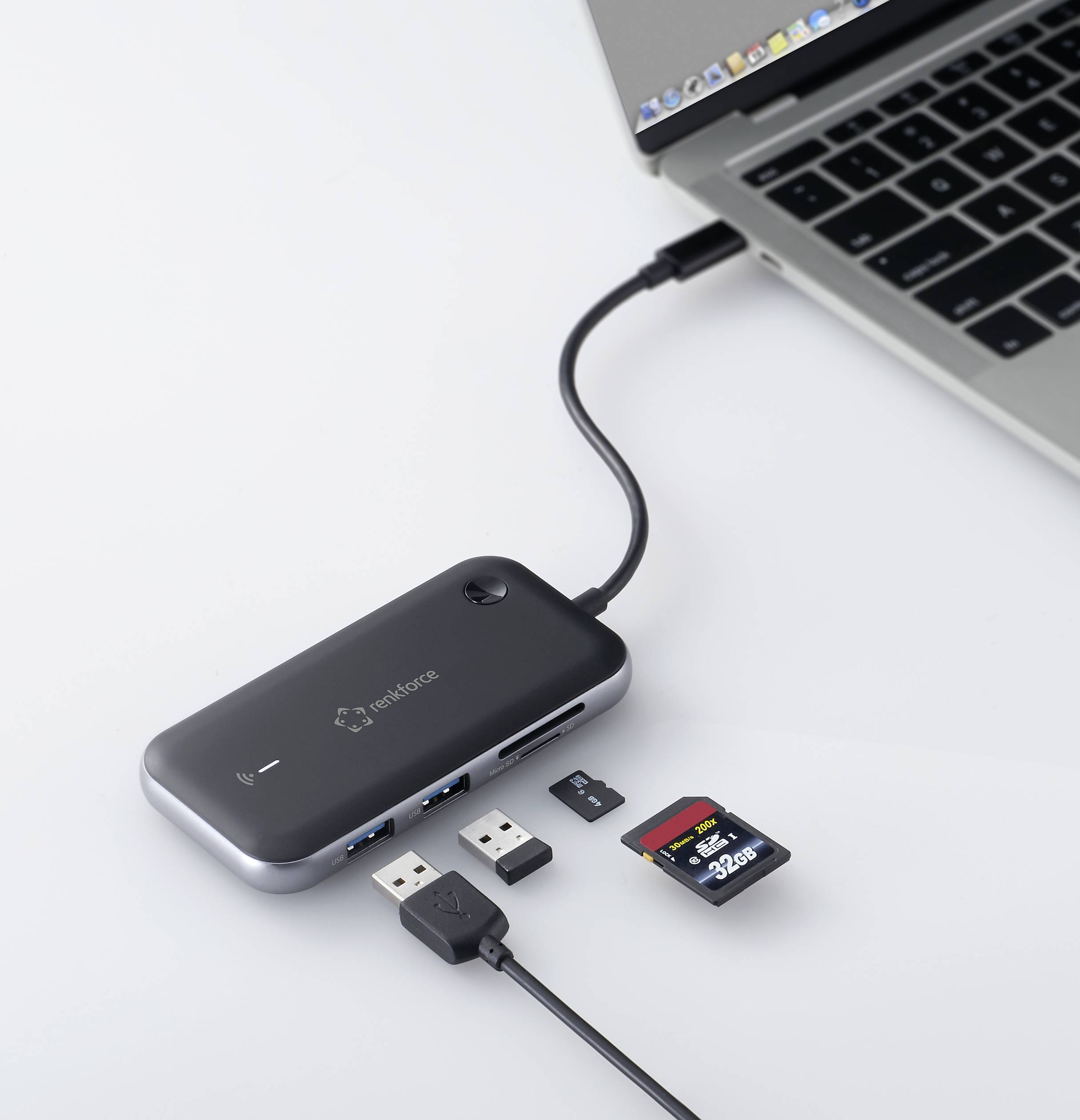 En bærbar computer er forbundet til en USB-hub via et USB-kabel. Ved siden af hubben ligger et SD-kort, et microSD-kort og en USB-nøgle.