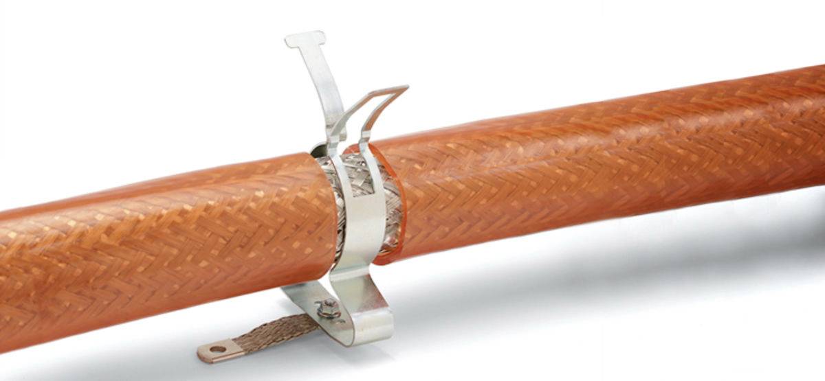 En orange flettet slange er fastgjort med en sølvfarvet klemme. Klemmen fastgør sikkert slangen på en overflade.