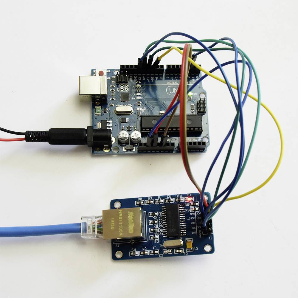 Arduino-bræt forbundet med flere farverige kabler til et Ethernet-shield. Opsætningen er beregnet til elektronisk styring og netværksforbindelse.