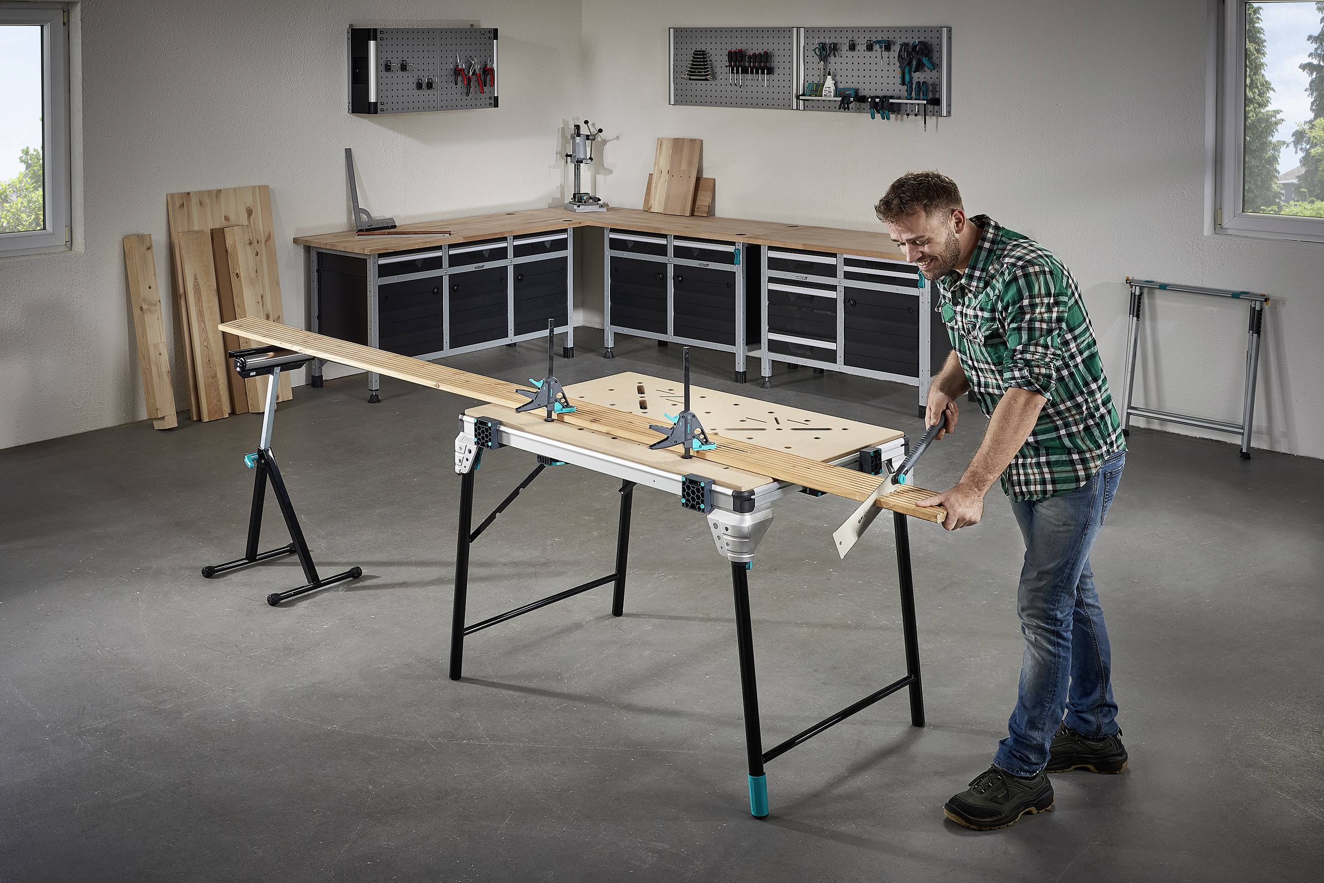 En mand saves et langt stykke træ ved et arbejdsbord i et værksted. I baggrunden står der værktøj og hylder.