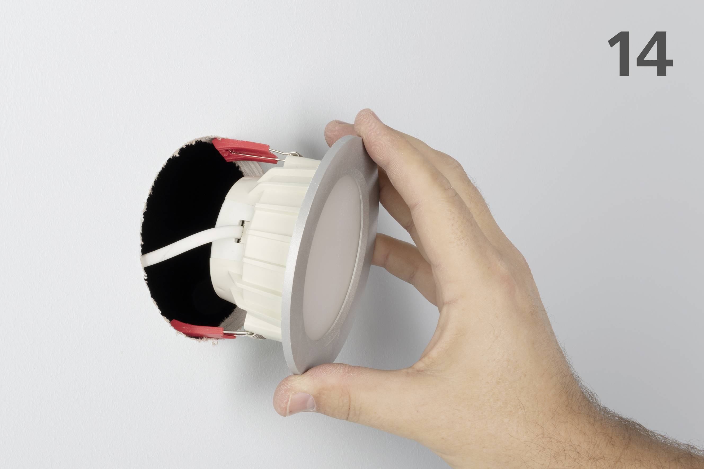 'Hånd installerer rund LED-lampe i loftet.'