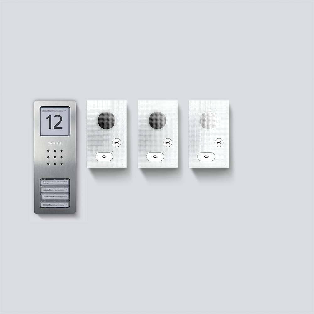 Et dørtelefon-panel med nummeret '12' ved siden af tre ringeklokker med højttalere og knapper på en lysegrå væg.
