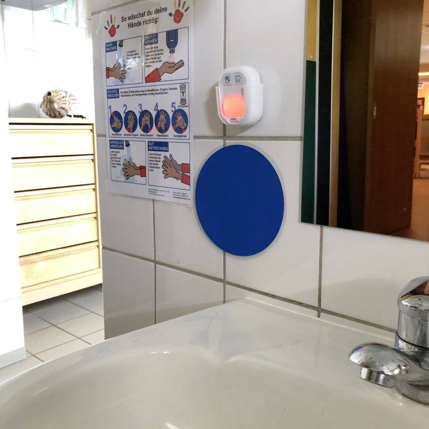 Håndvask med sæbedispenser. På væggen hænger en plakat med instruktioner til korrekt håndvask.