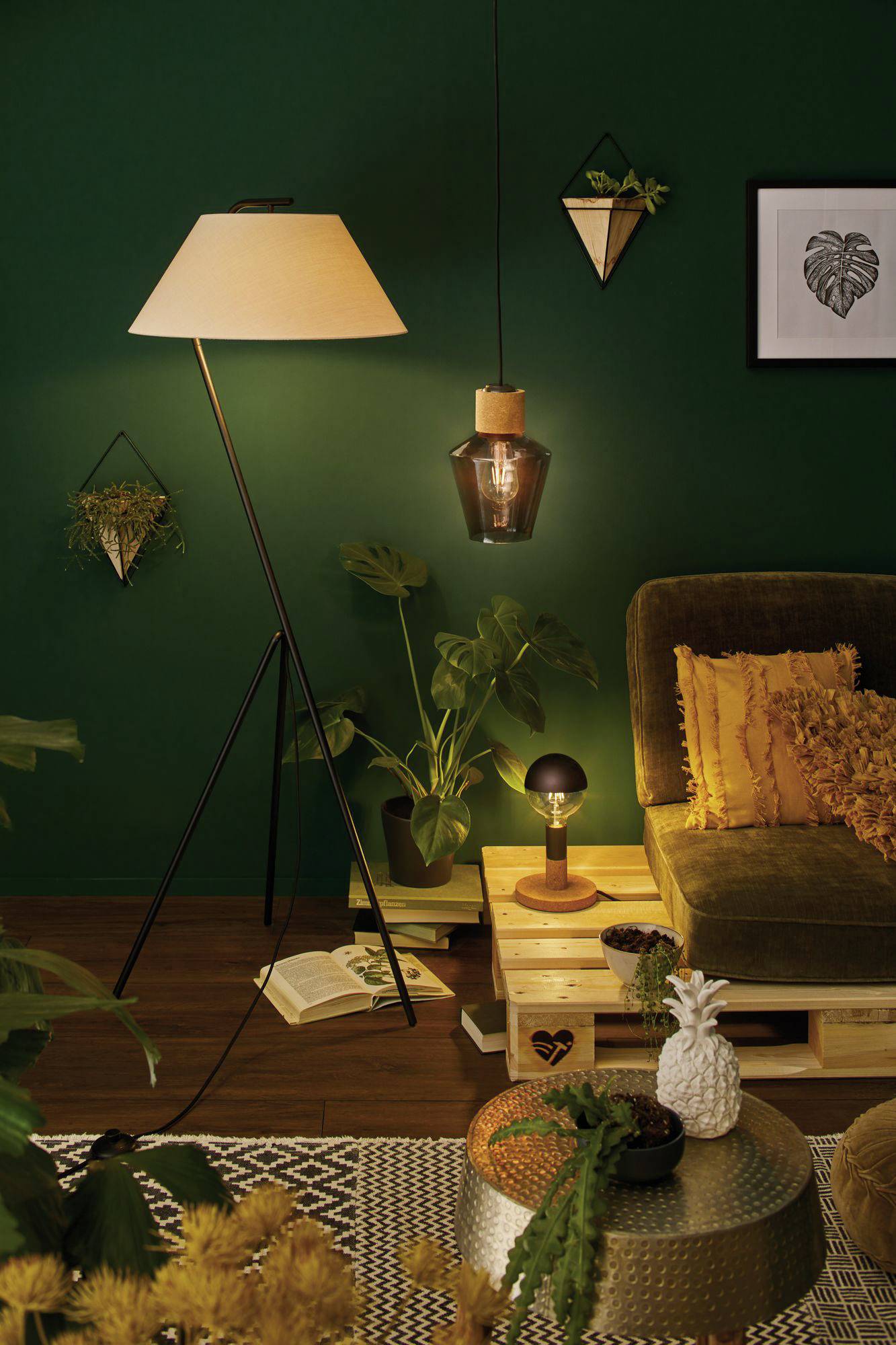 Et hyggeligt stue med gulvlampe, pendel og potteplanter. En sofa med gule puder og et sidebord med ananasdekoration.