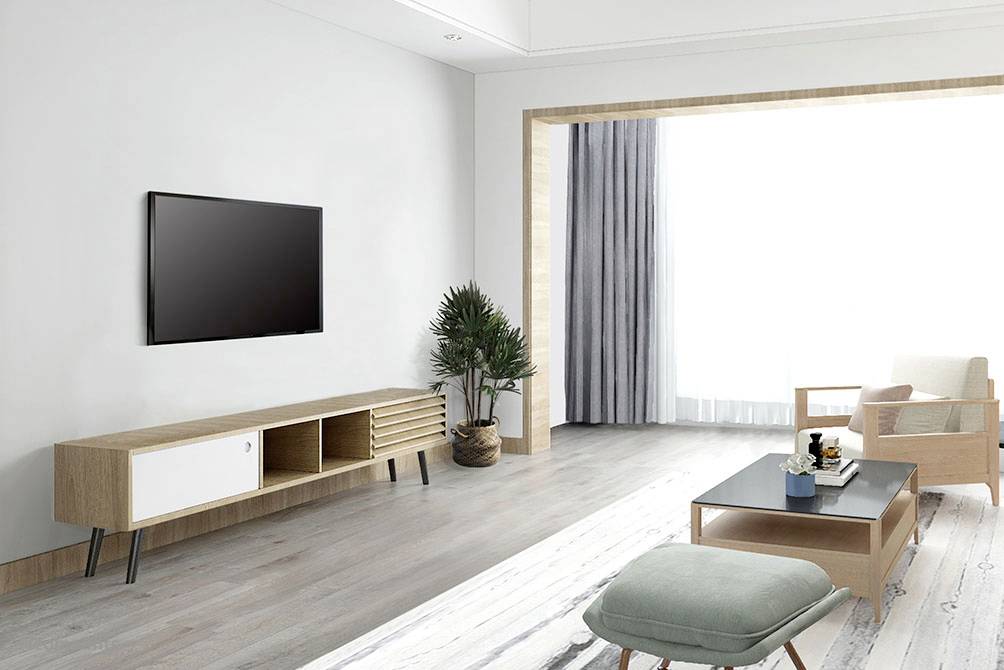Lyst, moderne stue med trægulv, TV på væggen, træmøbler, sofa og stort vindue med gardiner.