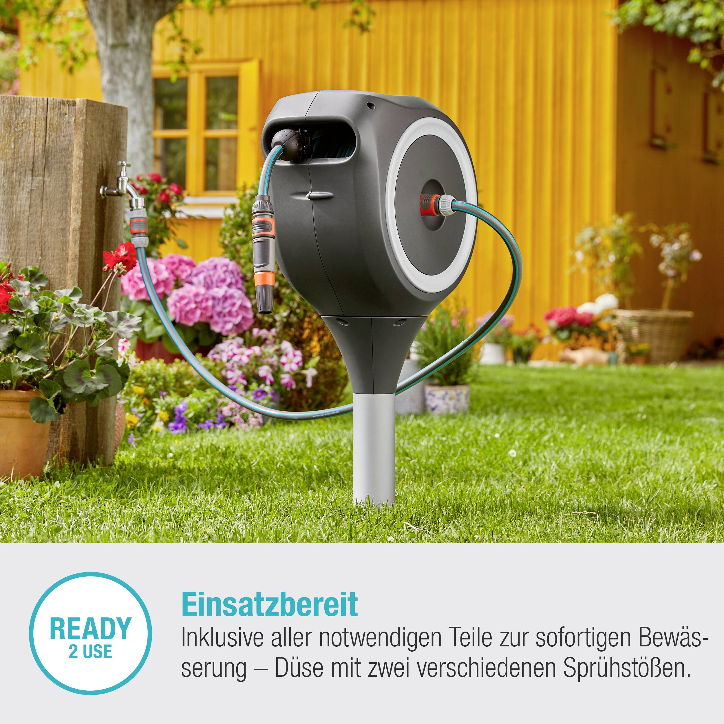 Haveslangeopruller i blomsterhaven. Klar til vanding med justerbar sprøjtedyse. Tekst: 'Klar til brug - READY 2 USE'.