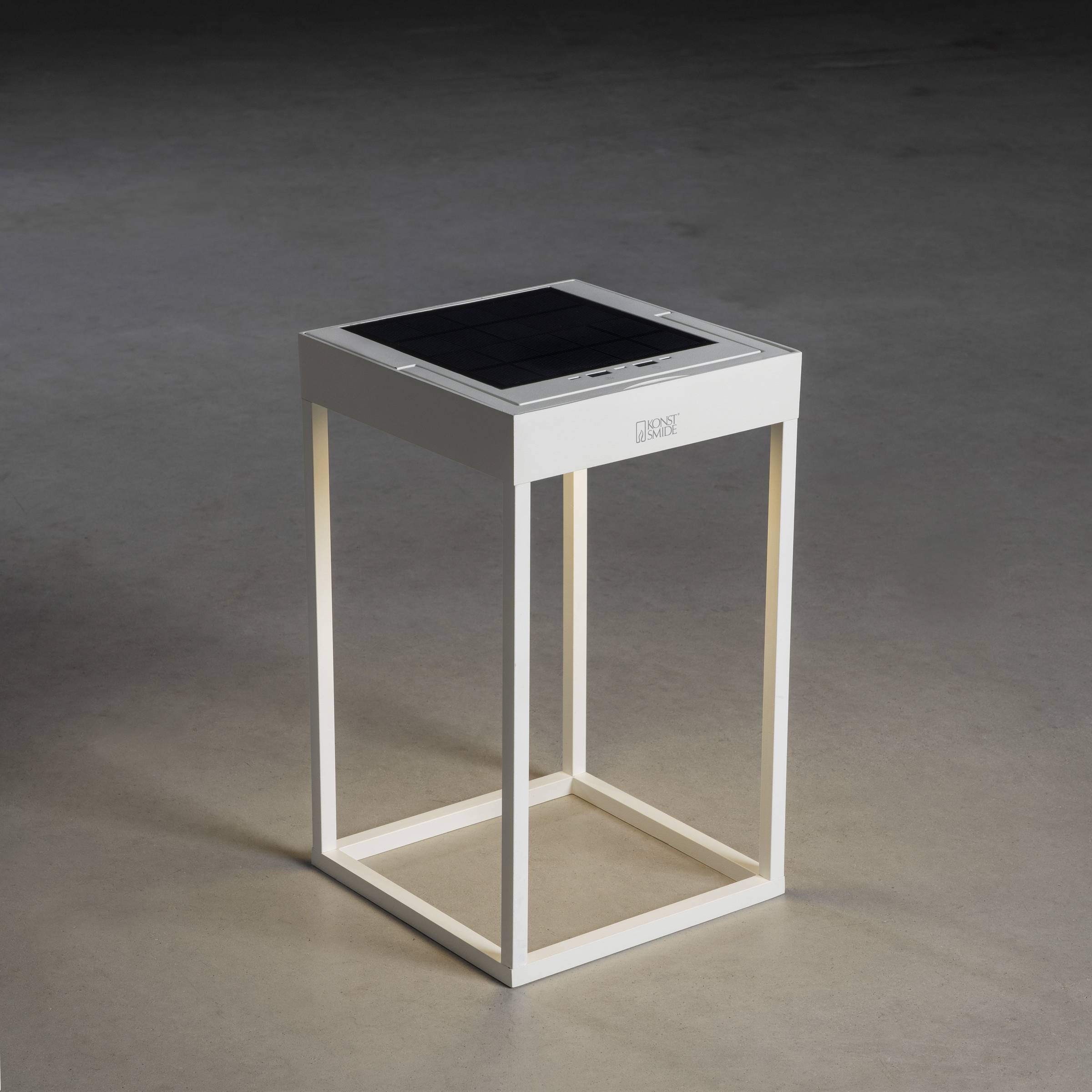 Et moderne hvidt bord med en firkantet glasplade og minimalistisk design står på et glat gråt gulv.