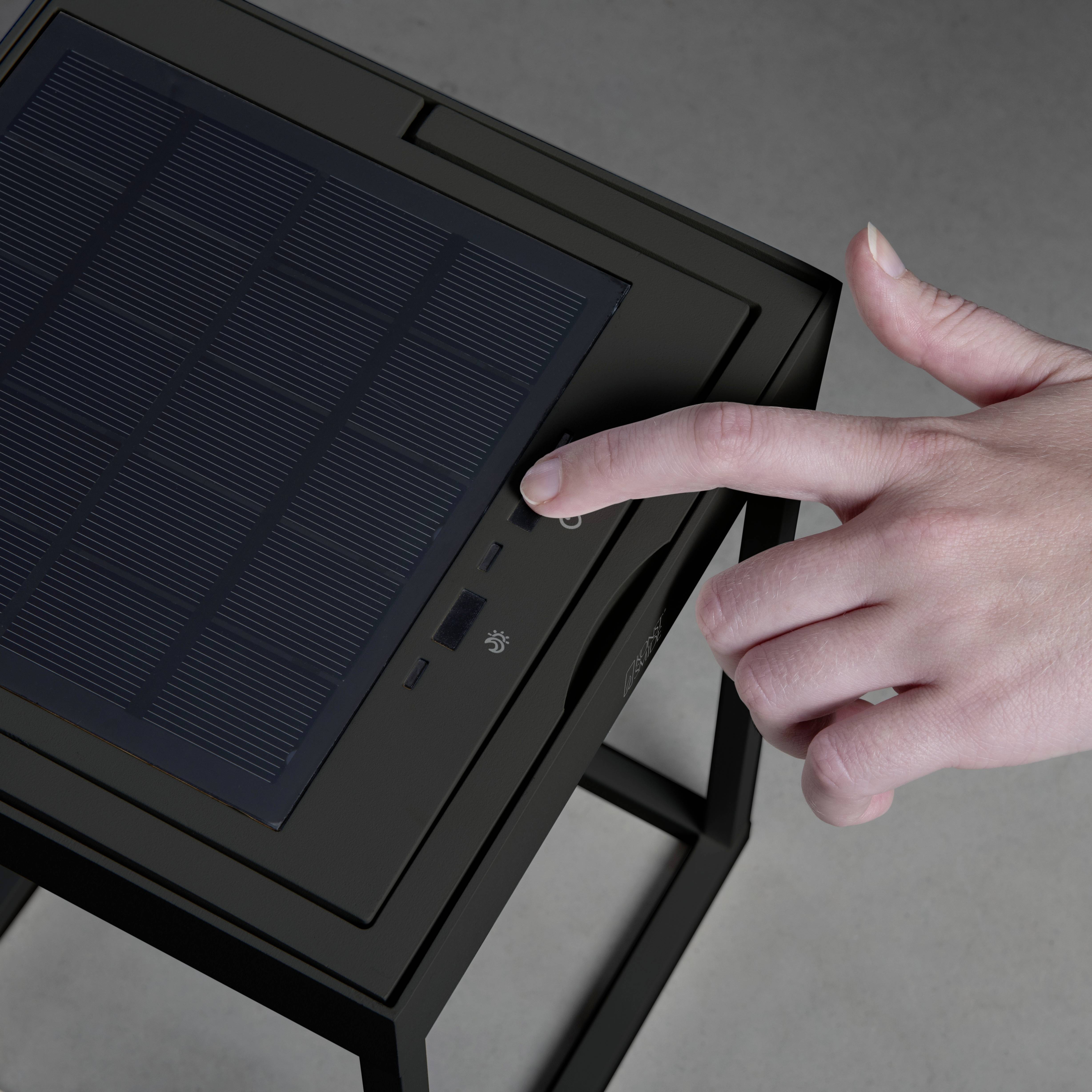 En hånd peger på et tablet med et solmodul, monteret på en metalramme.